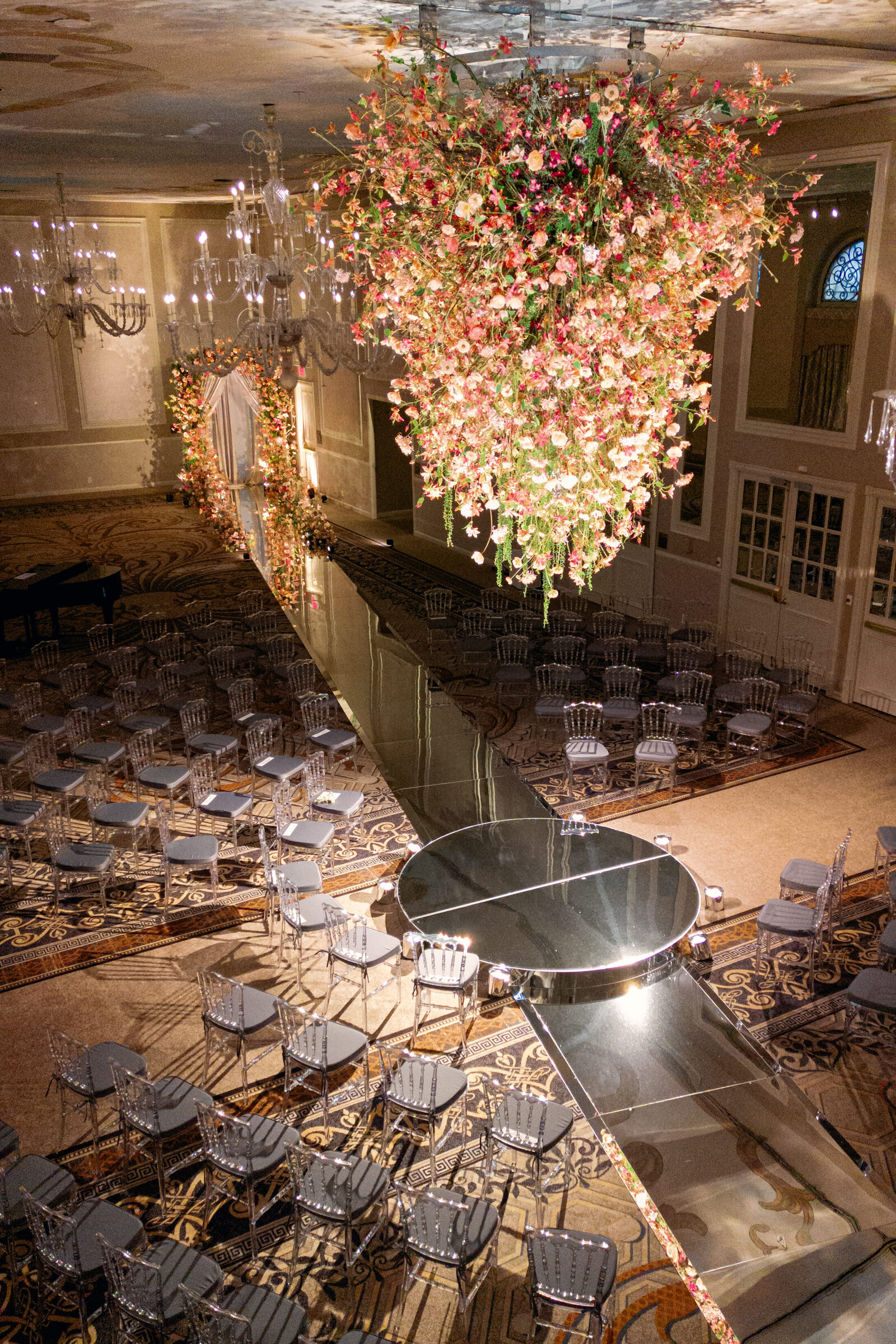 Grand hotel ballroom ceremony with a dramatic suspended installation and mirrored aisle