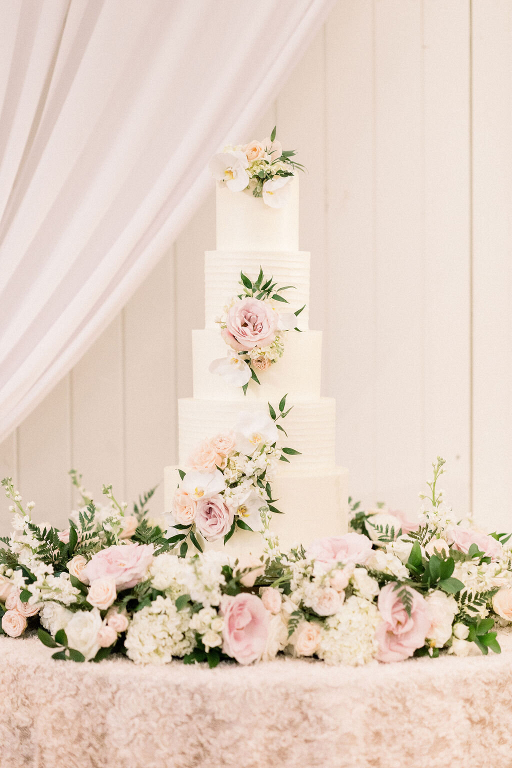 Tiered wedding cake before a softly draped backdrop