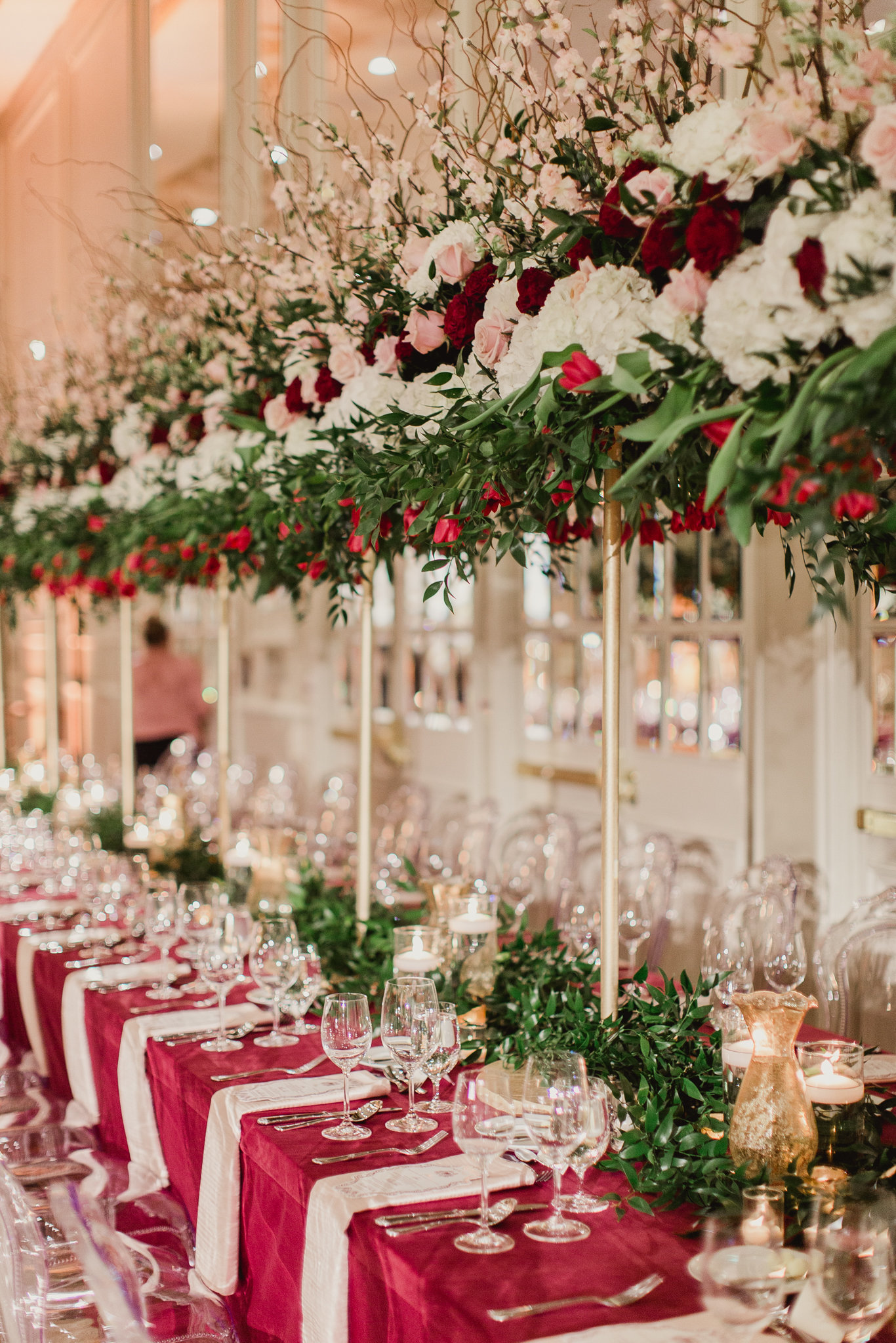 Long banquet reception table with a lush green runner and berry-toned linens