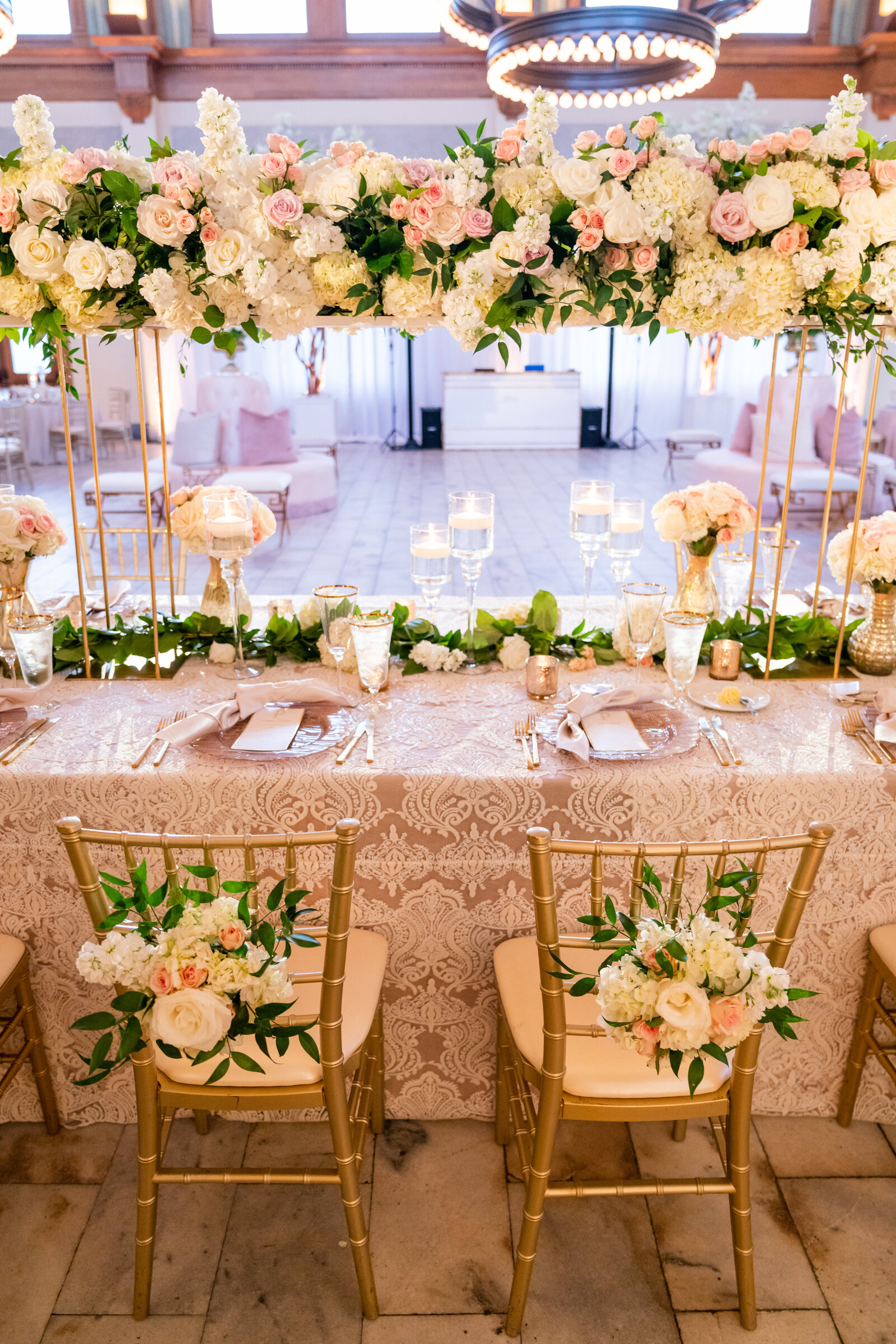 Ballroom wedding reception with round tables and a suspended halo installation